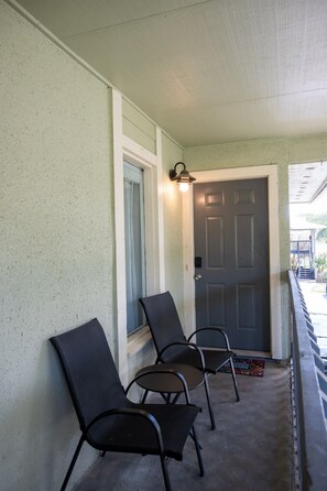A porch with three chairs, a door, and a light fixture. - Cozy Florida Retreat | Pool | Beach | Comfort (St. Augustine)