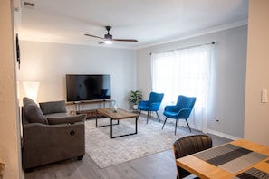 A living room with a sofa, a coffee table, a TV, and blue chairs. - Walk to beach, dining, pool, and all home comforts (St. Augustine)