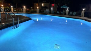 A swimming pool at night with steps leading into it, surrounded by a fence and a few lounge chairs. - Cozy Florida Retreat | Pool | Beach | Comfort (St. Augustine)