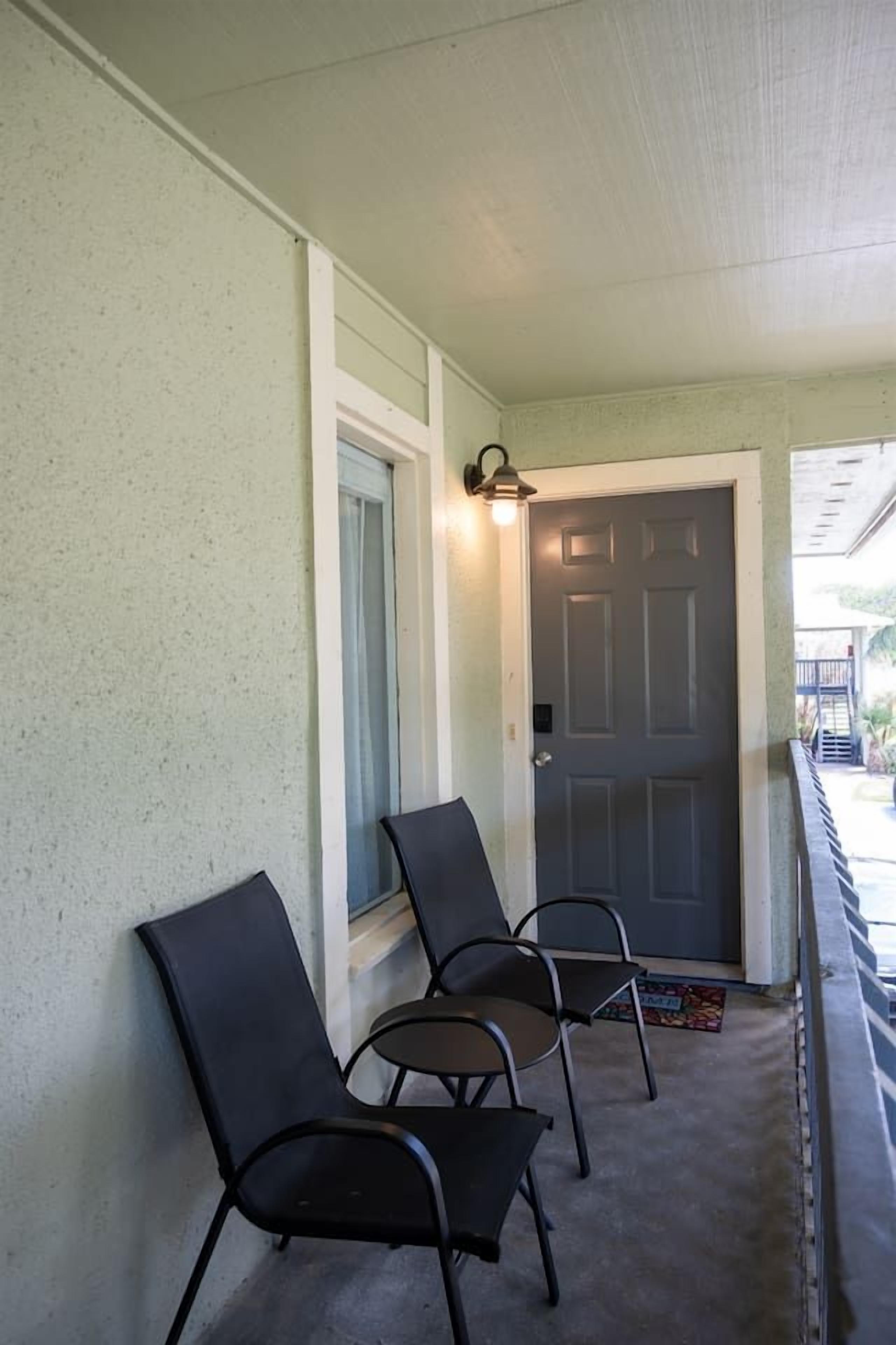 Een veranda met drie stoelen en een deur.