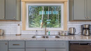 Una cocina con ventana, encimera de granito, lavaplatos de acero inoxidable y electrodomésticos modernos.