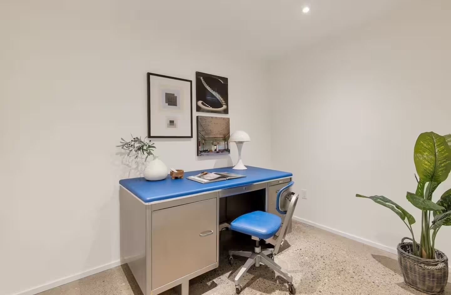A small office space with a desk, chair, and a potted plant.