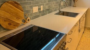 Una cocina con estufa integrada, un lavamanos y una ventana sobre él.