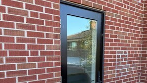 Un edificio de ladrillo rojo con una puerta negra y una cámara de seguridad encima.