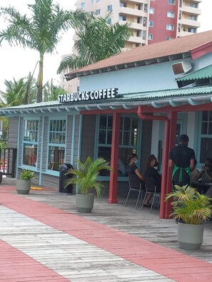 A Starbucks Coffee shop with outdoor seating, palm trees, and a red awning. - Towers by the Beach is a super studio apartment that is centrally located. (Ocho Rios)