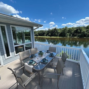 A deck with a table set for dining, overlooking a lake.