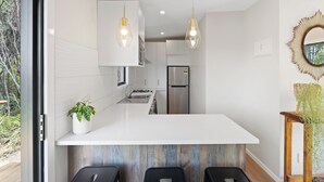 A modern kitchen with white cabinetry, a central island, pendant lighting, and a view of the outdoors.