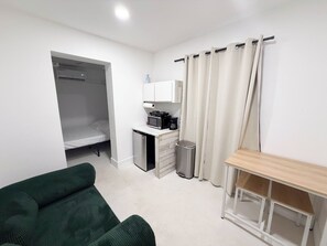 Ein kleines Zimmer mit Bett, Küchenzeile und einer kleinen Sitzecke.