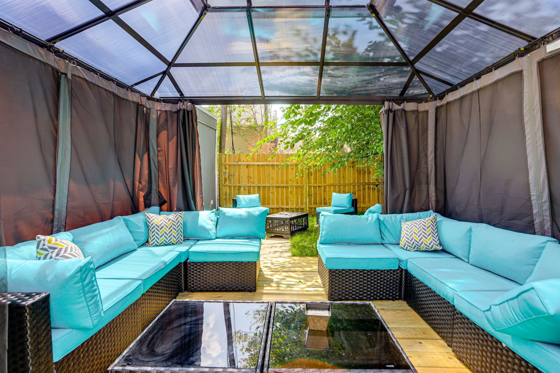 A covered outdoor seating area with a sectional sofa and a coffee table.