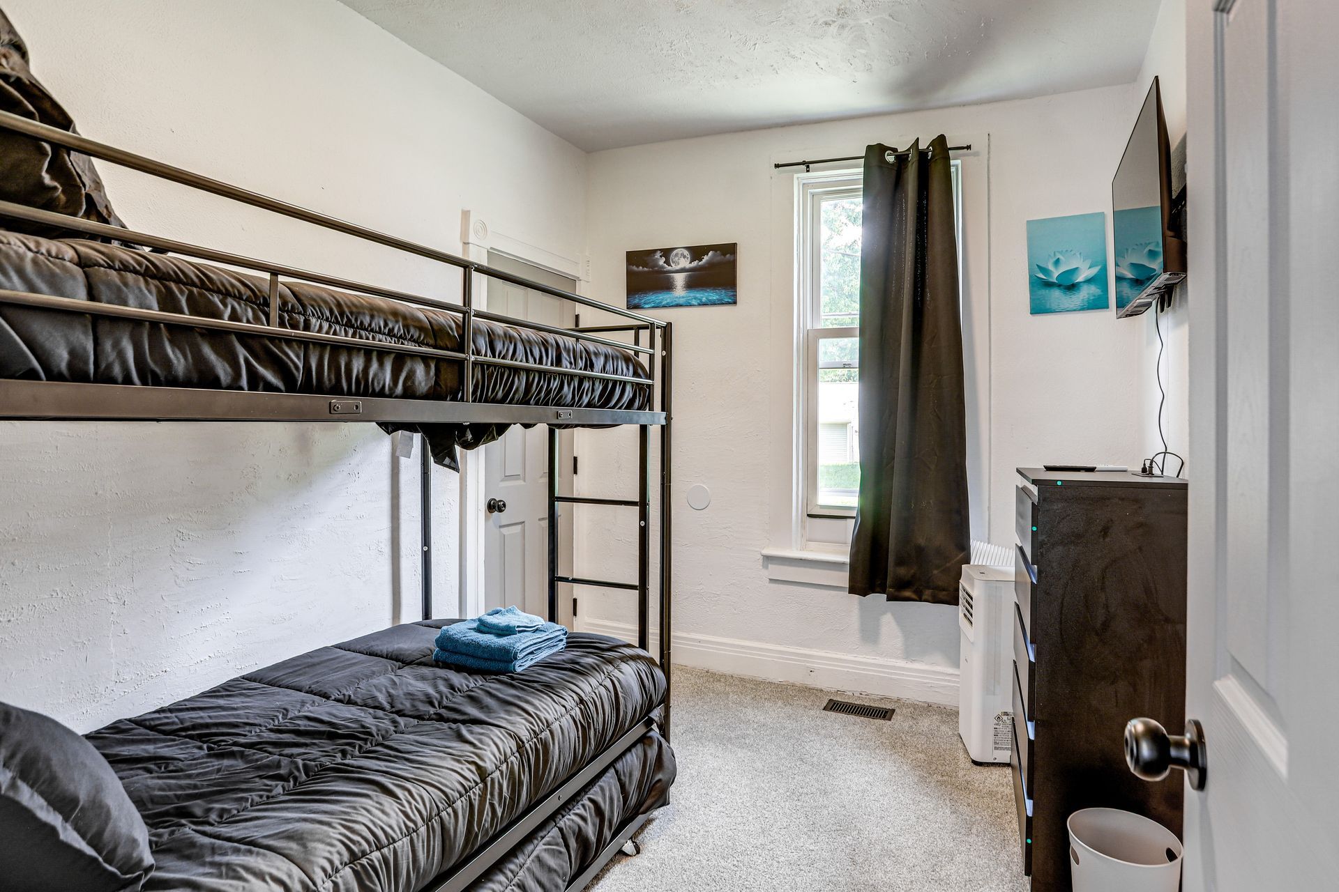 A bunk bed room with a desk and a window.