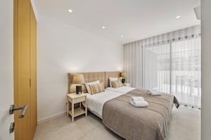 Ein modernes Hotelzimmer mit einem großen Bett, Nachttischen und Blick ins Freie.