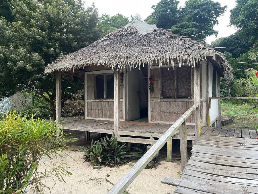 A small wooden structure with a thatched roof, a wooden deck, and a single door.