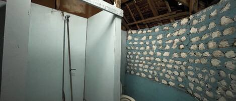 Un baño pequeño y rústico con techo de madera, un lavamanos blanco, un inodoro y una pared azul con diseño de piedra.