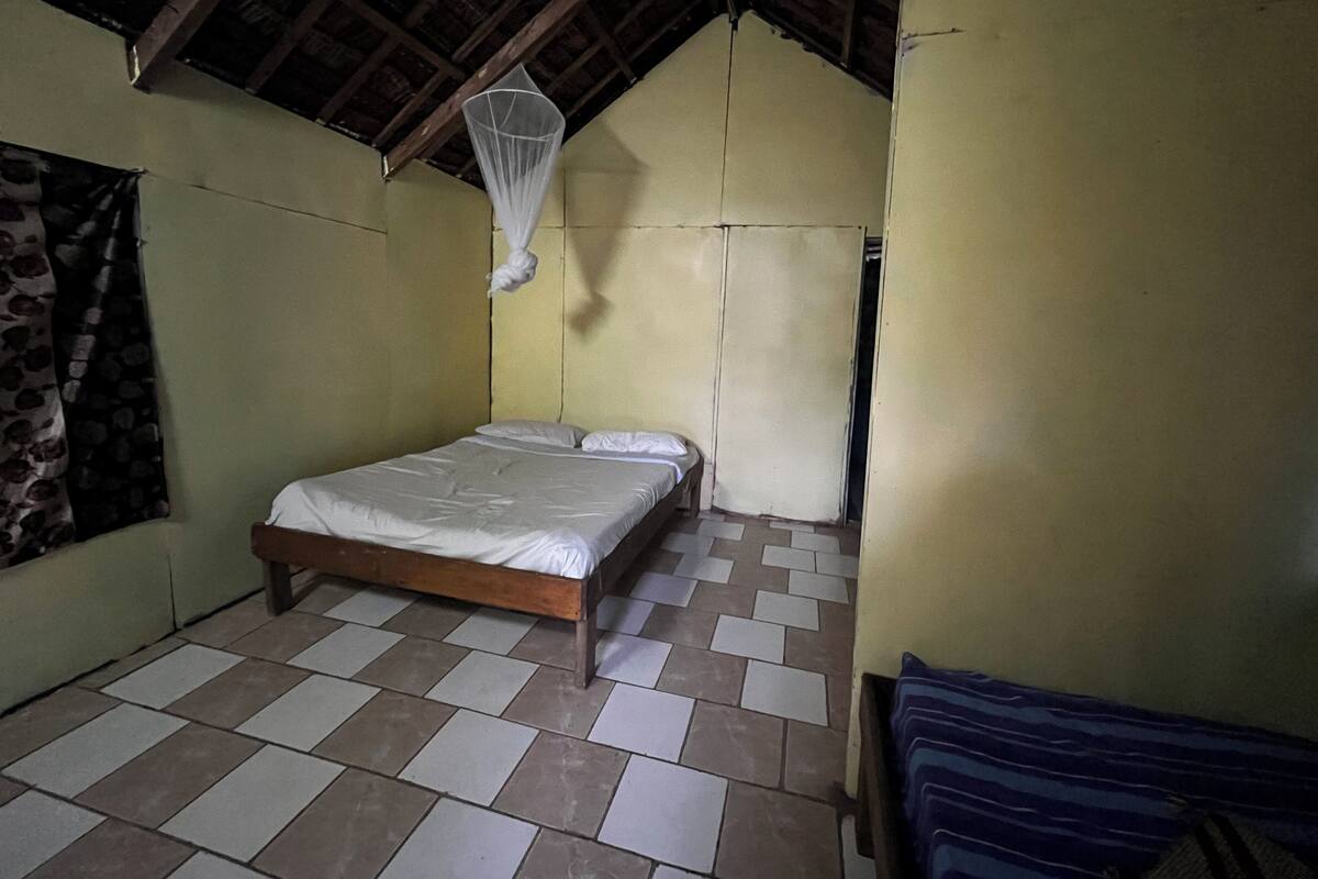 A room with a bed, a mosquito net, and a checkered floor.