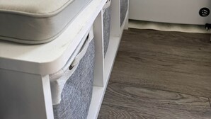 Un espace buanderie comprenant un lave-linge, un banc avec des coussins et un meuble de rangement pour suspendre le linge.
