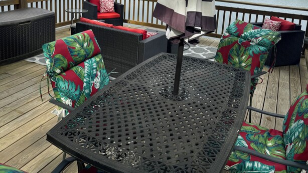 Une terrasse dotée de mobilier d’extérieur, d’une table et d’un parasol.