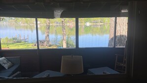 Une pièce avec vue sur un lac, une fenêtre avec un rideau, une table et une chaise.