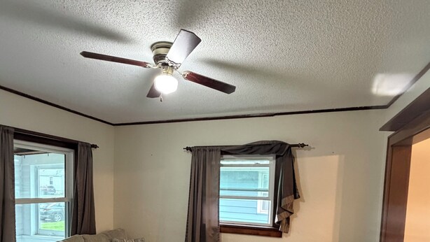 A living room with a sectional sofa, a round coffee table, a small side table, and a ceiling fan.