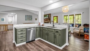 A spacious kitchen with a large island, green cabinets, and a dishwasher. - Big Mtn Home, Dog & Kid Friendly, close to Biltmore, breweries, & orchards (Hendersonville)