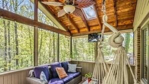 A covered porch with a wicker sofa, macrame hanging chair, and a ceiling fan. - Big Mtn Home, Dog & Kid Friendly, close to Biltmore, breweries, & orchards (Hendersonville)