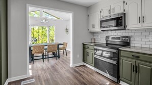 A modern kitchen with white cabinets, a built-in microwave, and an oven. - Big Mtn Home, Dog & Kid Friendly, close to Biltmore, breweries, & orchards (Hendersonville)