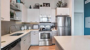 Una cocina moderna con electrodomésticos de acero inoxidable, armarios blancos y lavavajillas.