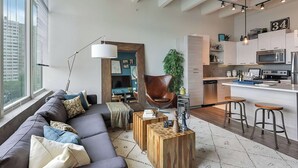 Una sala moderna con un sofá, una mesa de centro y un comedor con taburetes.