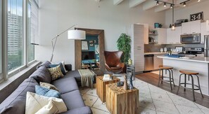 Ein modernes Wohnzimmer mit Sofa, Couchtisch und einer Essecke mit Hockern.