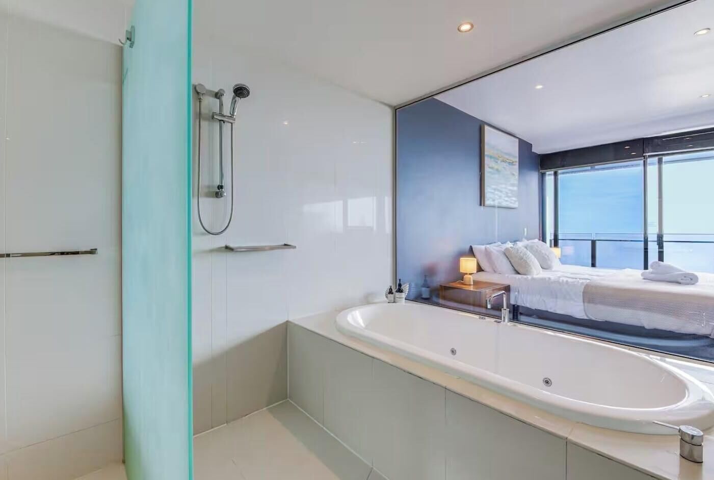Une salle de bain moderne dotée d’une grande baignoire, d’une douche et d’un lit avec vue.