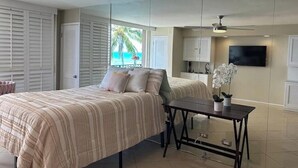 A bedroom with a bed, a small table, a TV, and a view of the ocean. - Penthouse level Waikiki Gold Coast- Spectacular Ocean View (Honolulu)
