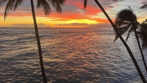 A sunset over the ocean with palm trees in the foreground. - Penthouse level Waikiki Gold Coast- Spectacular Ocean View (Honolulu)
