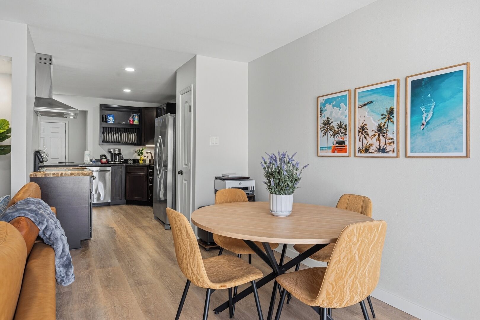 Une cuisine moderne dotée d’un îlot central, un coin repas avec une table ronde et des chaises, et un espace salon avec un canapé et une table basse.