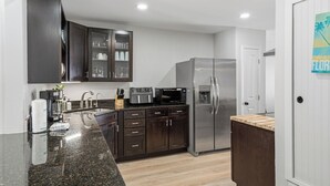 Una cocina moderna con armarios oscuros, un refrigerador de acero inoxidable, un microondas y una cafetera.