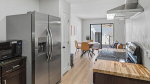 Una cocina moderna con un refrigerador de acero inoxidable, un microondas integrado y una estufa a gas.