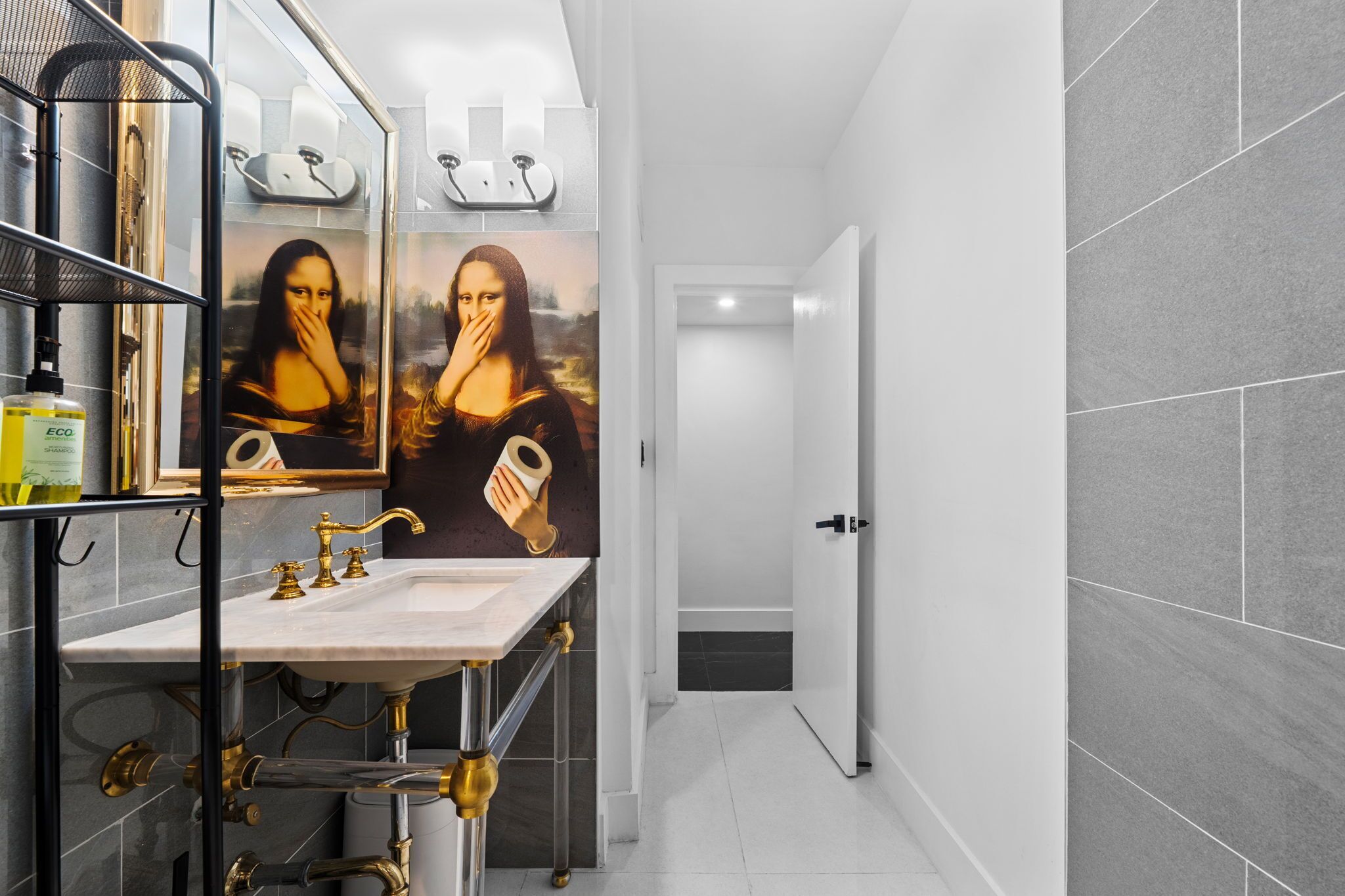A modern bathroom with a marble sink, gold faucets, and a mirror.