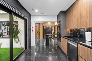 A modern kitchen with black countertops, wooden cabinets, and a central island. - Beautiful 2BR/2BA Oasis with Pool, Gym & Private Parking (Miami)