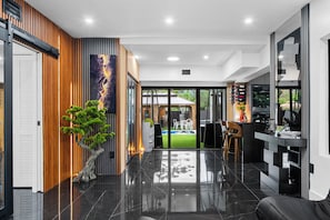 A modern interior with a polished floor, a dining area with chairs, and a view of a backyard. - Beautiful 2BR/2BA Oasis with Pool, Gym & Private Parking (Miami)