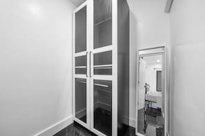 A hallway with a white closet and a mirror reflecting a bathroom with a bed and a radiator. - Beautiful 2BR/2BA Oasis with Pool, Gym & Private Parking (Miami)