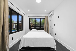 A bedroom with a bed, a window, and an air conditioning unit. - Beautiful 2BR/2BA Oasis with Pool, Gym & Private Parking (Miami)