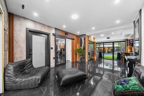 A modern interior with a leather sofa, a black ottoman, and a glass coffee table. - Beautiful 2BR/2BA Oasis with Pool, Gym & Private Parking (Miami)