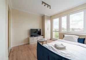 Ein Schlafzimmer mit einem Bett, einem Fernseher, einem kleinen Tisch und einem Fenster mit Blick.
