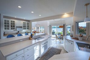 A modern kitchen with white cabinetry, a central island, and a view of a patio with outdoor seating. - The Loon at Intermediate | Pets | Hot Tub | Golf (Bellaire)