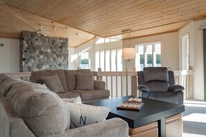 Ein geräumiges Wohnzimmer mit Steinwand, großem Fenster und Deckenventilator.