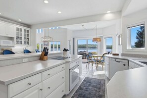 A modern kitchen with white cabinetry, a large island, and a view of the outdoors.
