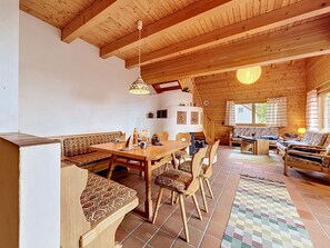 Un interior de madera con comedor, asientos y una escalera.