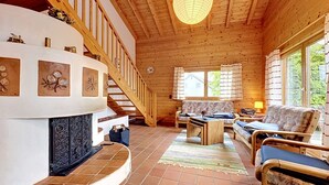 Un interior de madera con chimenea, una escalera y una zona de sofás.