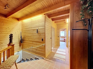 Un intérieur en bois avec un escalier, un banc et une porte.