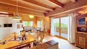 Interior de madera con comedor, sofá y balcón con vistas.