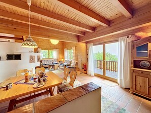 Interior de madera con comedor, sofá y balcón con vistas.