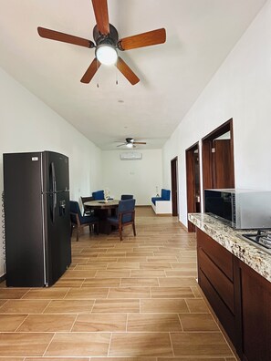 A kitchen with a refrigerator, microwave, and stove. There is a dining area with chairs and a table. - Casa y departamentos Nacho (Puerto Vallarta)